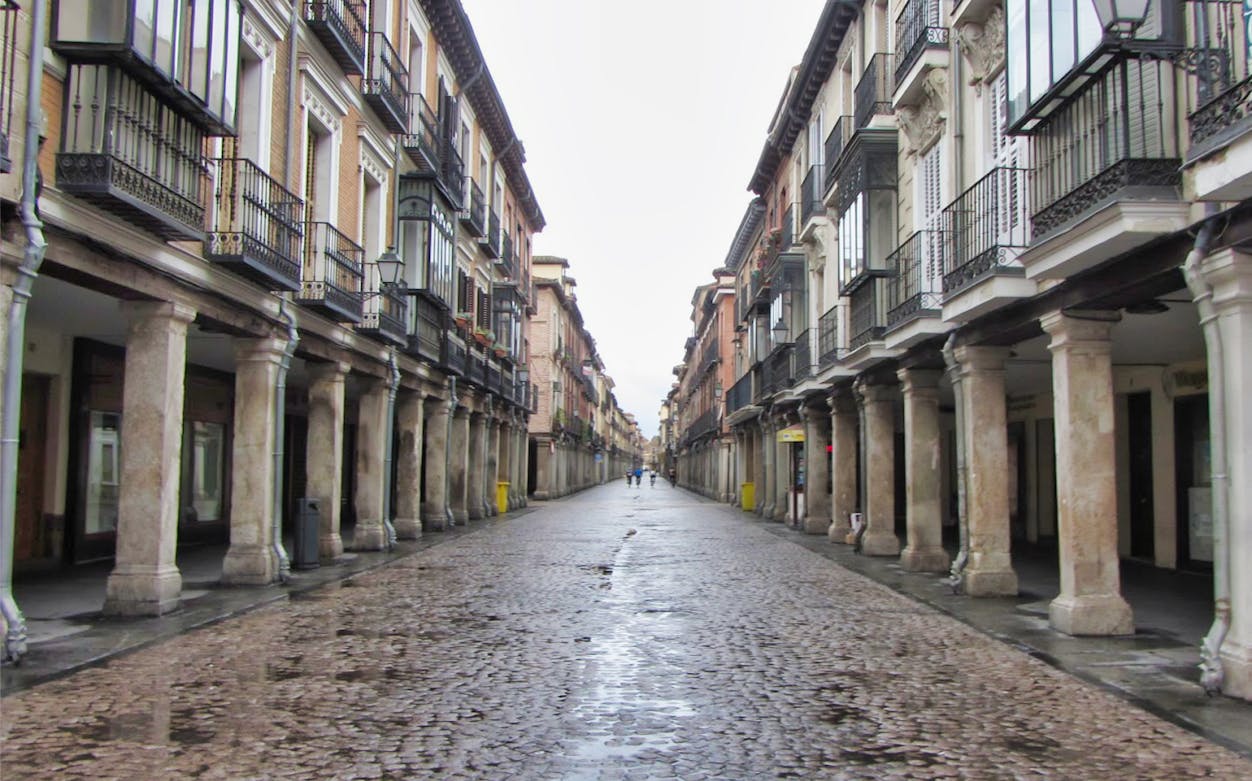 Calle Mayor in Alcala de Henares with historic colonnades and cobblestone street.