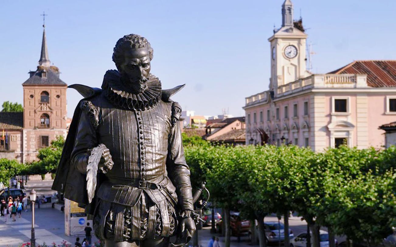Statue of Cervantes in Plaza de Cervantes, Alcala de Henares, with historic buildings in the background.