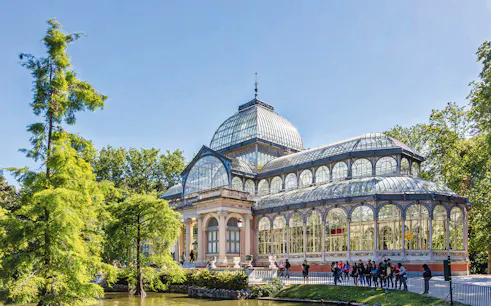 Retiro Park Crystal Palace with visitors on a guided tour in Madrid, Spain.
