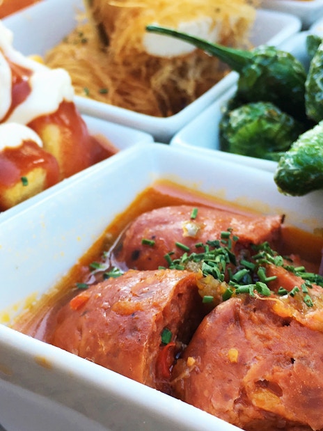 Tapas dishes with chorizo, patatas bravas, and peppers on a Triana tour.