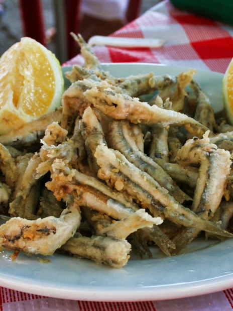 Fried fish with lemon slices on a plate during a guided tapas tour in Triana.