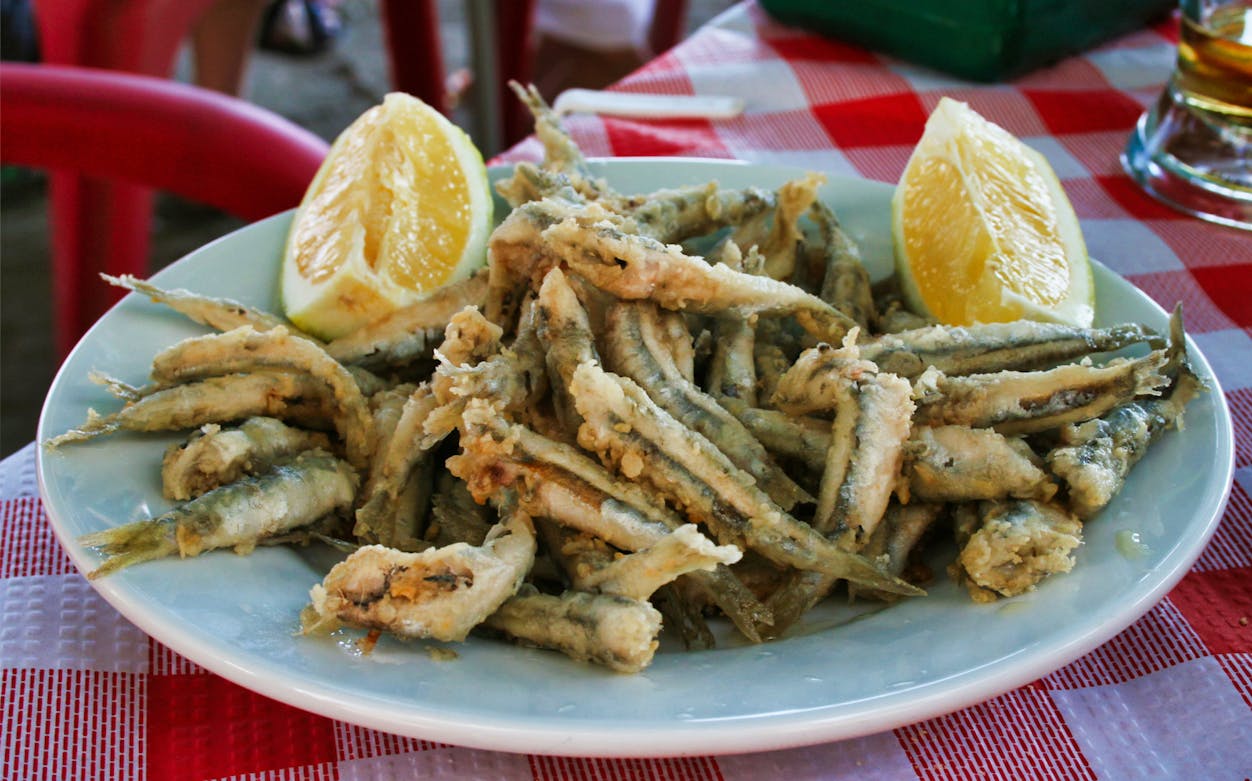 Fried fish with lemon slices on a plate during a guided tapas tour in Triana.