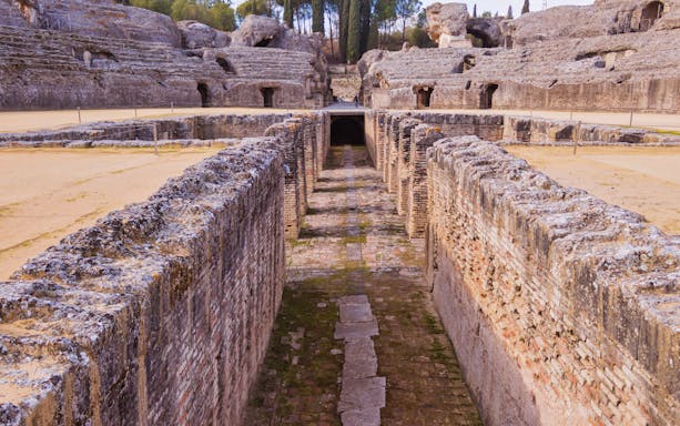 Ruins of Italica amphitheater with ancient stone walls and pathways in Santiponce, Spain.