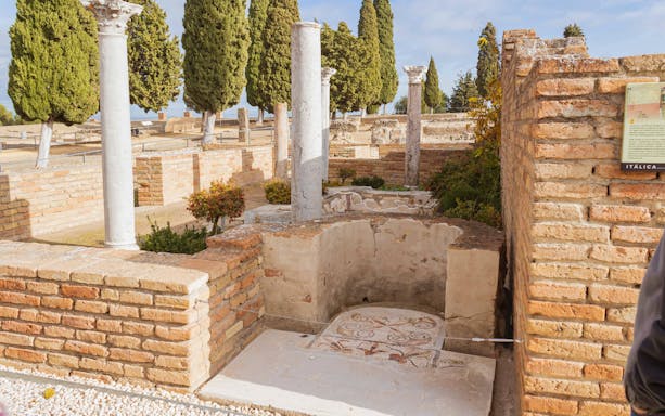 Ruins of Italica with ancient mosaic and stone columns.
