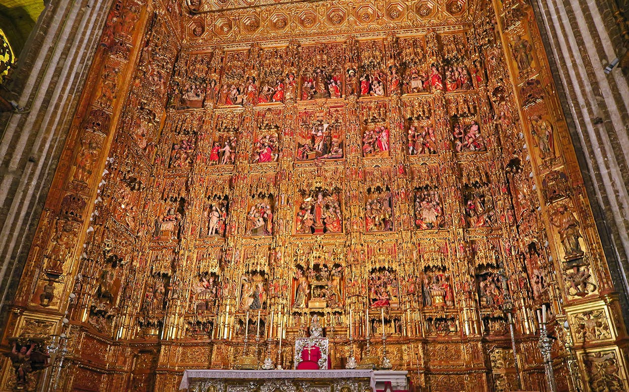 Seville Cathedral's ornate golden altarpiece, showcasing intricate Gothic carvings.
