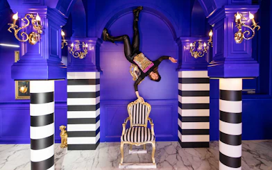 Person upside down in a blue room with striped columns, part of Upside Down Canal Cruise experience.
