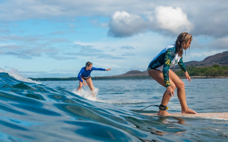 Surfers learning to ride waves during a lesson in Maui, Hawaii.