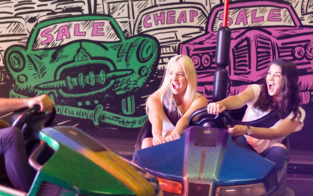 Bumper car ride at Luna Park Sydney with colorful graffiti backdrop.