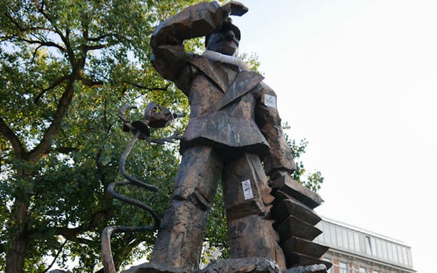 Statue on Reeperbahn tour in Hamburg, Germany, surrounded by trees.