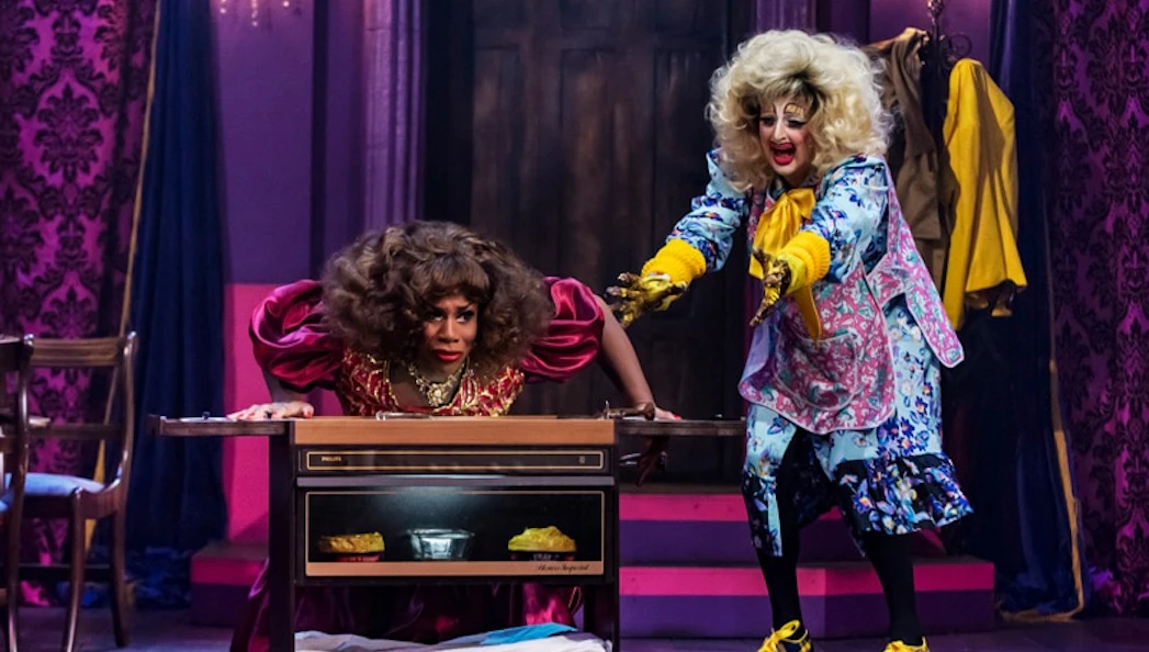 Two performers in colorful costumes on stage during "Death Drop Back in the Habit" show.