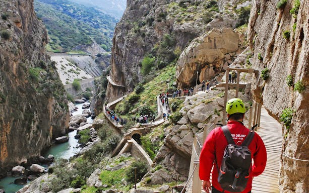 Guided tour group walking along Caminito del Rey path in Ardales canyon.