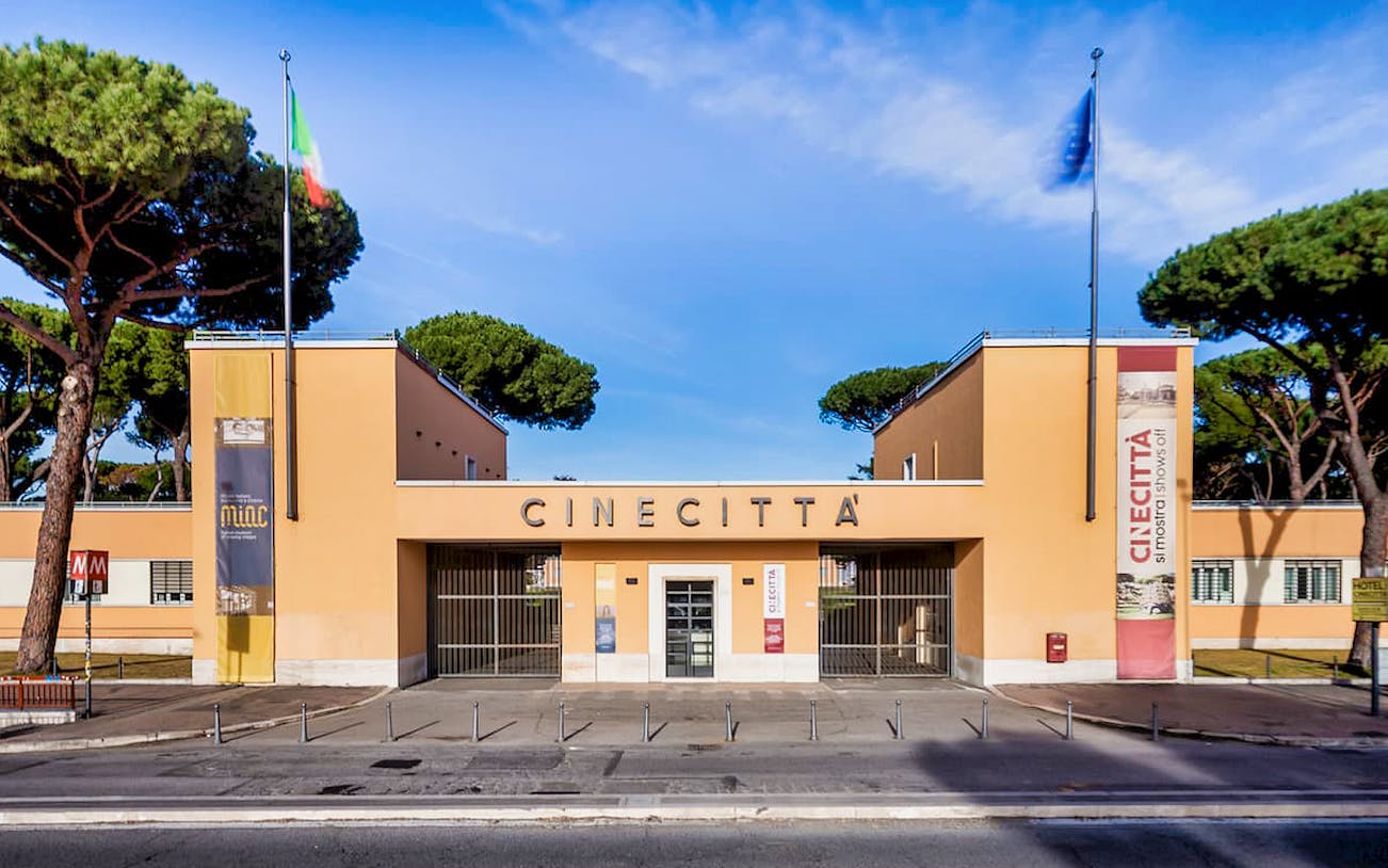 Cinecittà entrance in Rome with flags and trees, showcasing the iconic film studio.