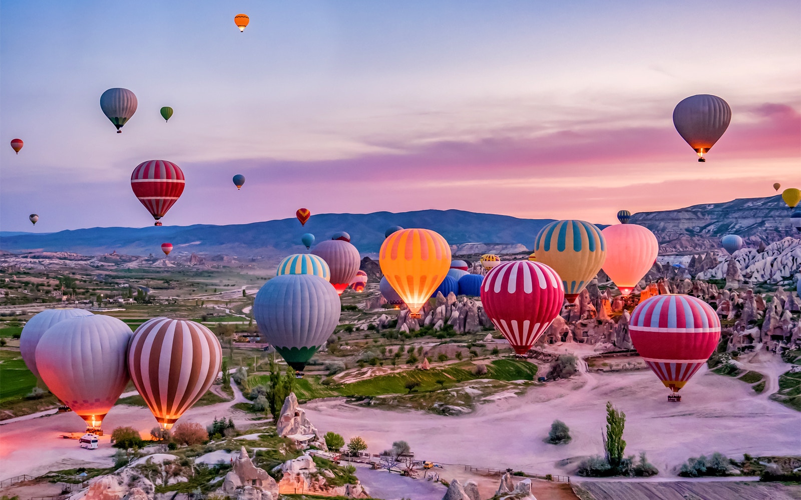 Hot air balloons over Cappadocia's fairy chimneys at sunrise.
