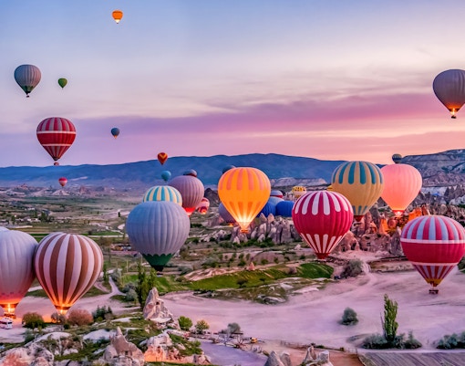 Hot air balloons over Cappadocia's fairy chimneys at sunrise.
