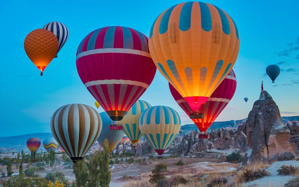 Hot air balloons flying over the Fairy Chimneys in Cappadocia at sunrise.