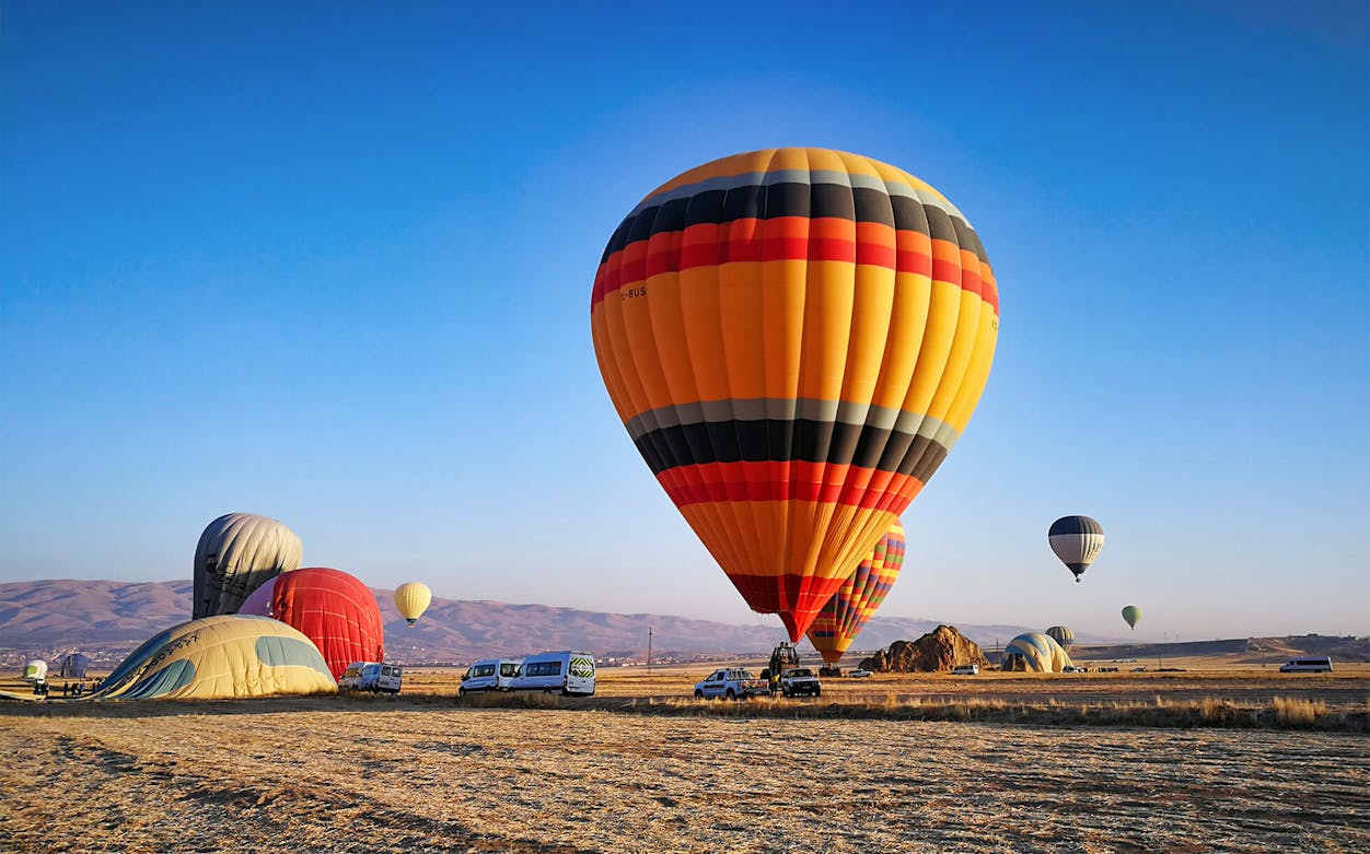 Hot air balloons preparing for flight over a scenic landscape during a 1-hour tour.