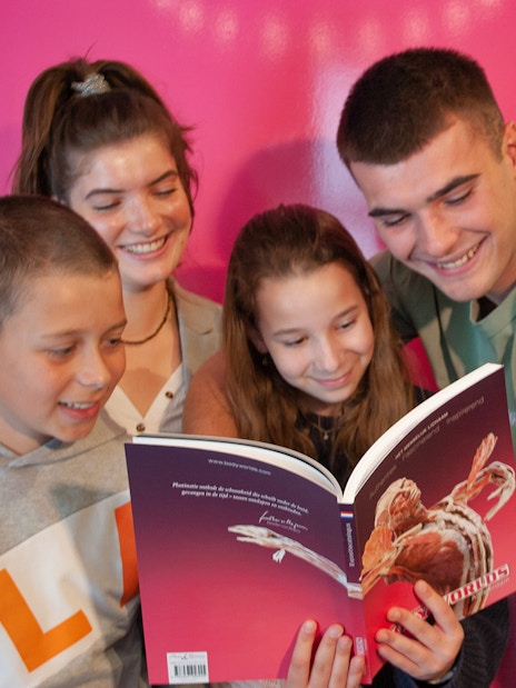 Group of people reading a Body Worlds Amsterdam book together.