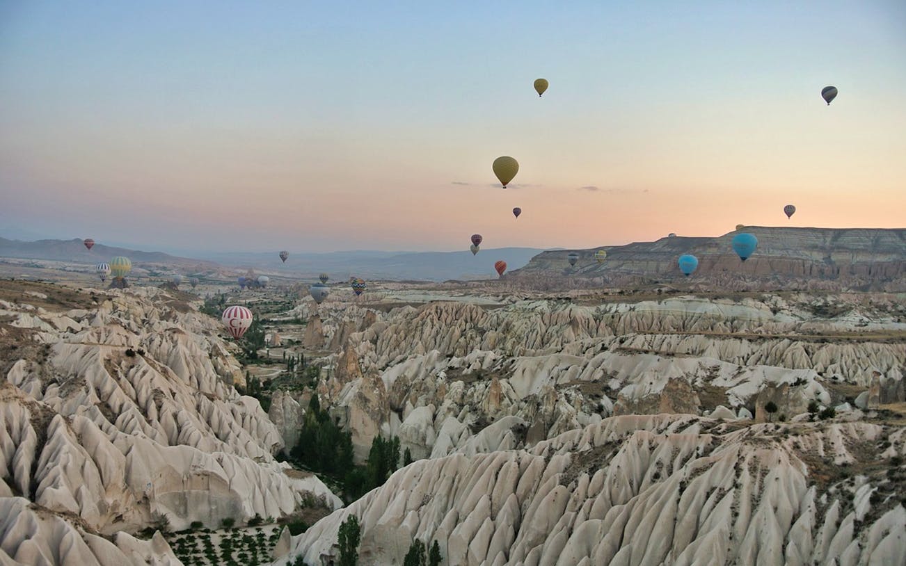 Hot air balloons over Cappadocia's unique rock formations at sunrise.