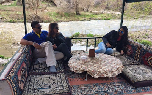 Group relaxing on traditional Turkish seating by a river in Cappadocia during Uchisar Castle tour.
