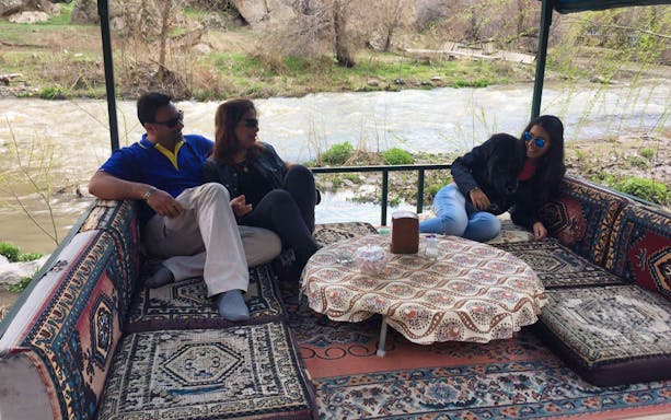 Group relaxing on traditional Turkish seating by a river in Cappadocia during Uchisar Castle tour.