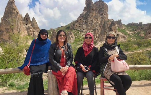 Visitors at Cappadocia with Uchisar Castle rock formations in the background.
