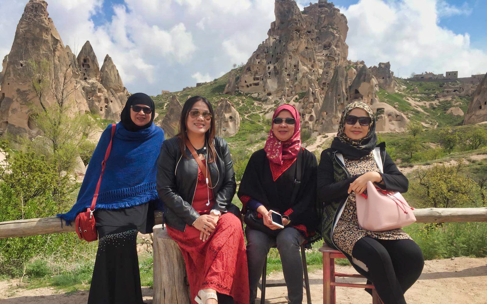 Visitors at Cappadocia with Uchisar Castle rock formations in the background.