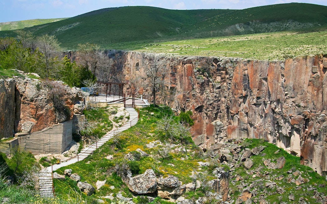 Pathway along Ihlara Valley canyon in South Cappadocia, surrounded by greenery and rock formations.
