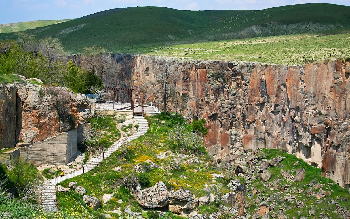 Pathway along Ihlara Valley canyon in South Cappadocia, surrounded by greenery and rock formations.