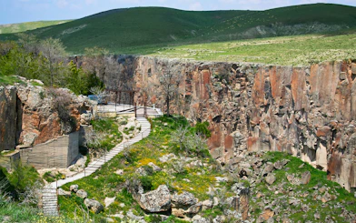 Pathway along Ihlara Valley canyon in South Cappadocia, surrounded by greenery and rock formations.