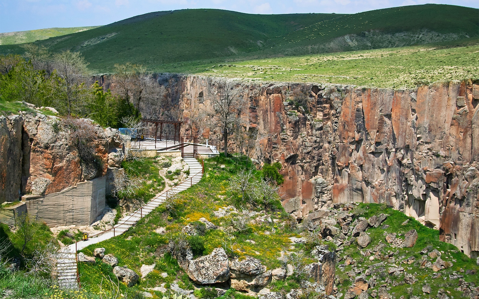 Pathway along Ihlara Valley canyon in South Cappadocia, surrounded by greenery and rock formations.