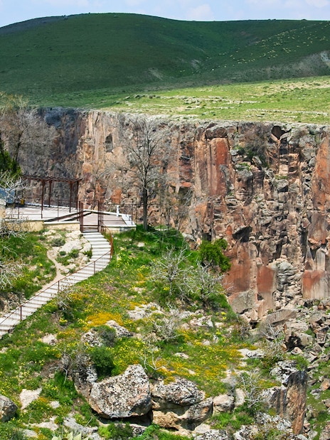 Pathway along Ihlara Valley canyon in South Cappadocia, surrounded by greenery and rock formations.