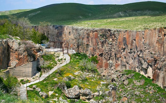 Pathway along Ihlara Valley canyon in South Cappadocia, surrounded by greenery and rock formations.
