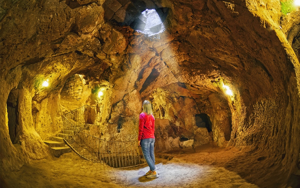 Person exploring an ancient underground cave in South Cappadocia.