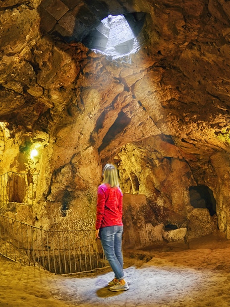 Person exploring an ancient underground cave in South Cappadocia.