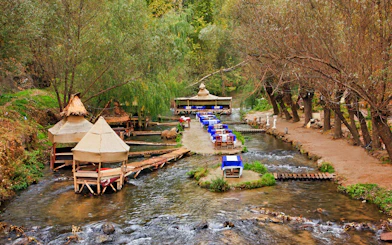 Outdoor dining setup along a stream in South Cappadocia, surrounded by trees.