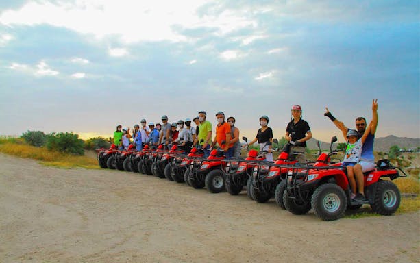 Group on quad bikes ready for safari tour with transfers in scenic landscape.