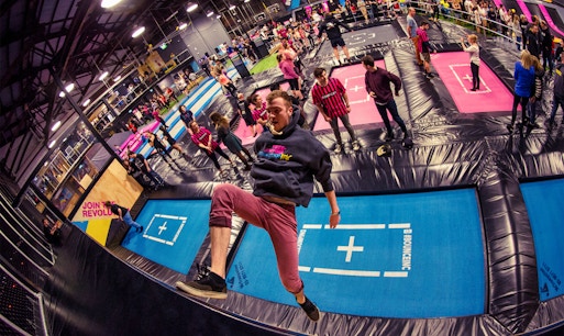 Indoor trampoline park with various trampolines and foam pits at Bounce Abu Dhabi.
