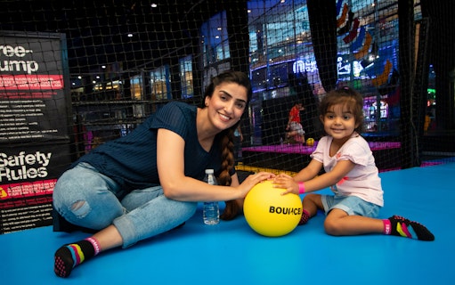 Adults and child playing with a yellow ball at Bounce Abu Dhabi trampoline park.