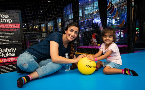 Adults and child playing with a yellow ball at Bounce Abu Dhabi trampoline park.