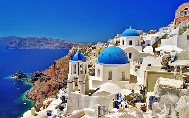 White buildings with blue domes overlooking the sea in Santorini, Greece.