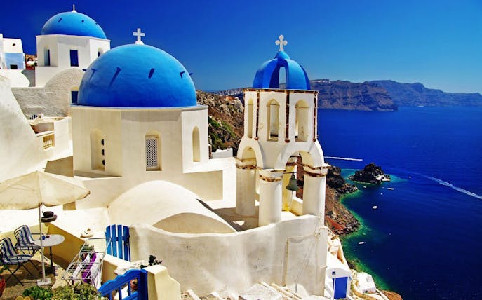 Santorini's blue-domed churches overlooking the Aegean Sea on a Caldera morning boat tour.