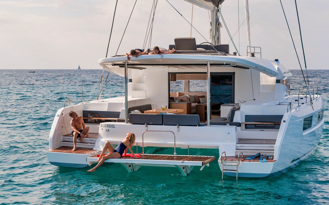 Catamaran with people relaxing on deck during Santorini Ultimate Sailing Cruise Experience.