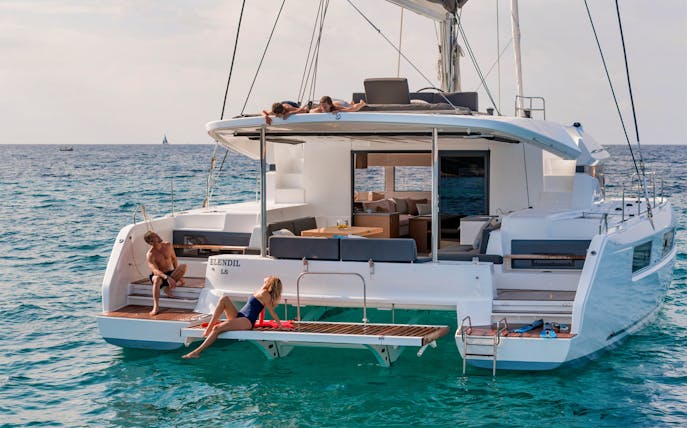 Catamaran with people relaxing on deck during Santorini Ultimate Sailing Cruise Experience.