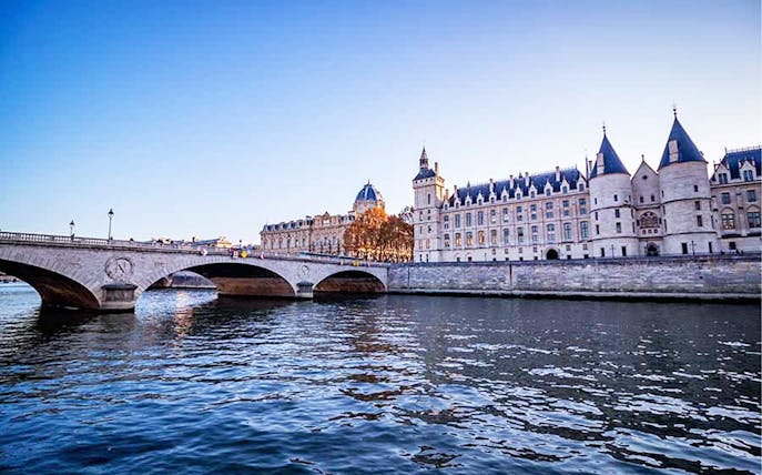 Conciergerie and bridge over Seine River in Paris during a river cruise.