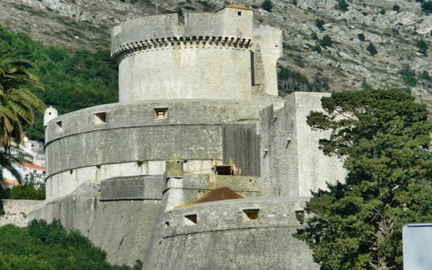Dubrovnik city walls with stone fortifications and lush greenery.