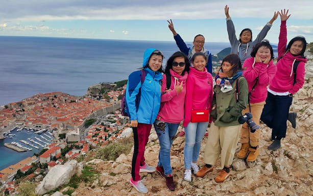 Group enjoying a view of Dubrovnik's old town from a hilltop.