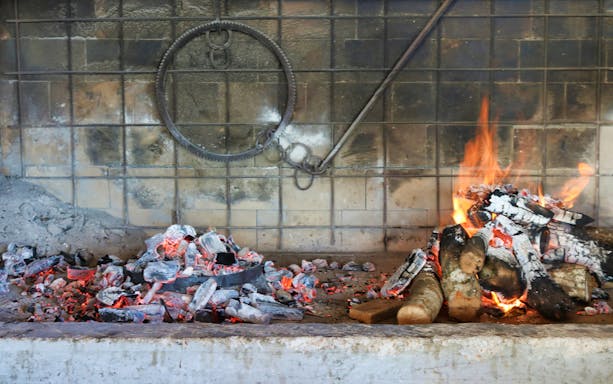 Traditional wood-fired oven with burning logs in Dubrovnik market.