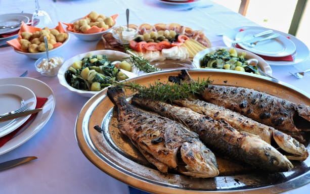 Grilled fish and local dishes on a table during Dubrovnik food and market tour.