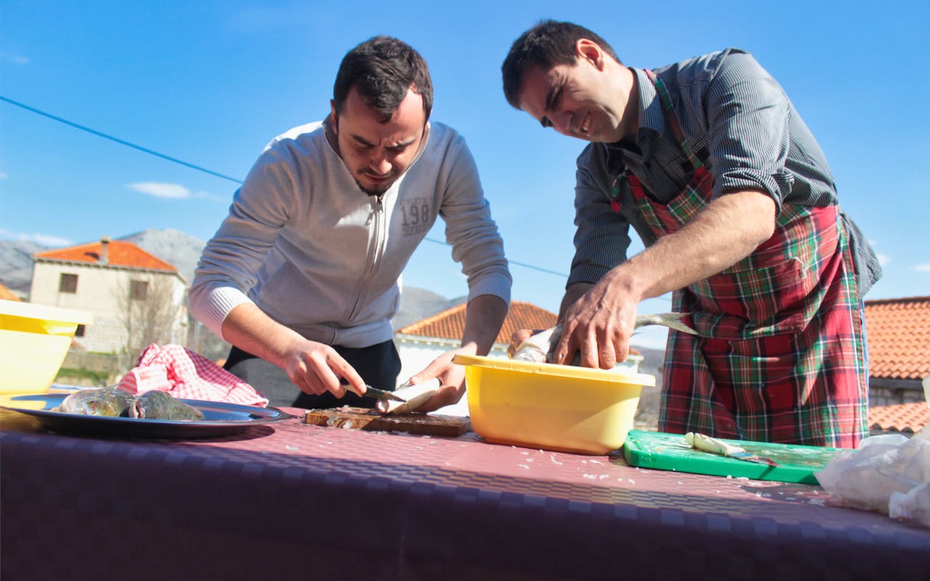 Men preparing fish outdoors during Dubrovnik food and market tour.