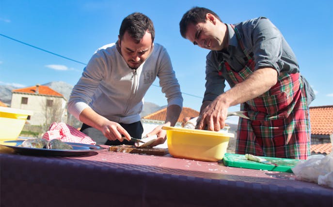Men preparing fish outdoors during Dubrovnik food and market tour.